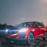 red 2019 acura rdx with headlights on parked under starry sky in desert