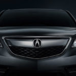 front view of gray or black acura with dark background and white lights